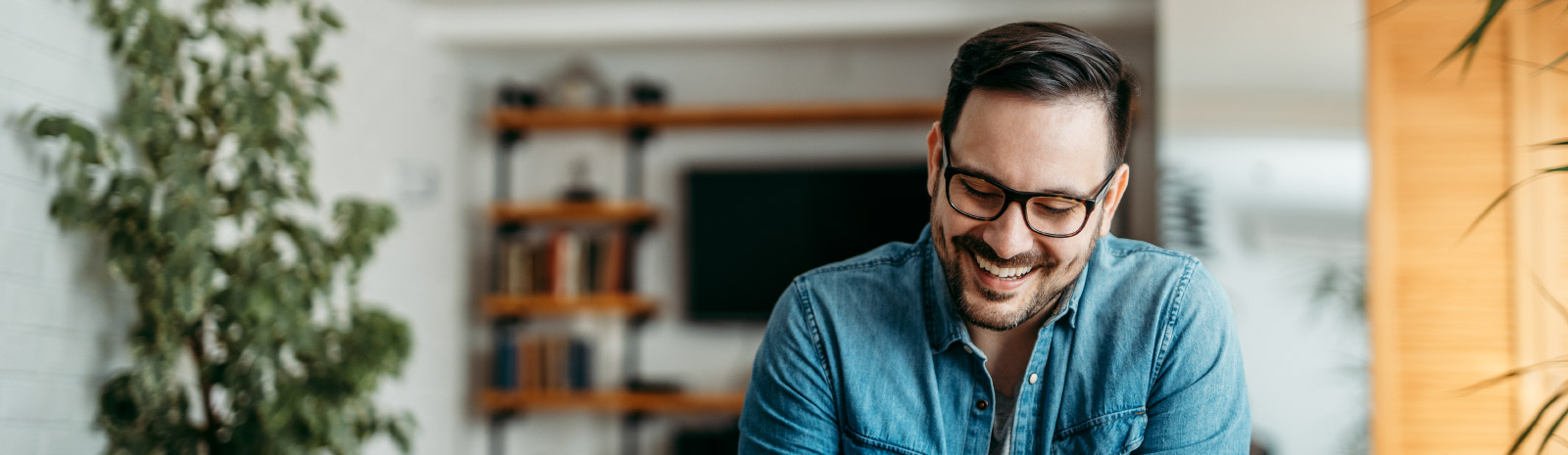 Man in glasses smiling and looking down